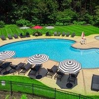 A pool surrounded by lawn chairs and umbrellas.